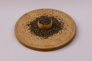 Healhty chia seeds spilling out of wooden bowl on wooden plate