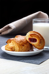 Breakfast with milk with a croissant on a white plate