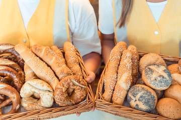 Verkäuferinnen in Bäckerei präsentieren frisches Brot in einem Brotkorb