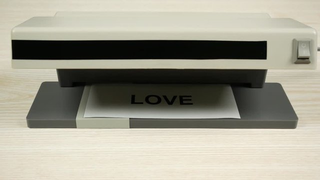 The word love on paper changes under the ultraviolet to the word fake. The concept of insincere love.