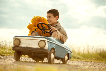 Young boy driving a vintage toy car, beautiful sunny day