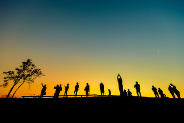 Silhouette of tourist group watching beautiful sunrise on the mountain.  Dawn light with copy space.