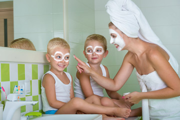 Obraz na płótnie Canvas Mother and children make a face mask in the morning.The boys joke with mom. Beauty treatments for the skin 