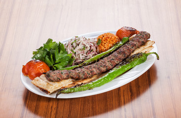 Turkish kebab served with yoghurt and vegetables on wooden table