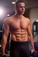Fototapeta na wymiar Young adult bodybuilder lifting weight in gym.