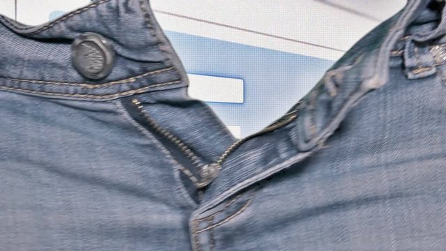 The hands of a woman opening the zipper of a pair of jeans, revealing a login sequence on a computer screen / website, inserting username and password and clicking the button.
