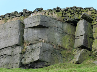 dramatic stone outcrop in yorkshire moors with craggy sandstone texture and drystone walling along...