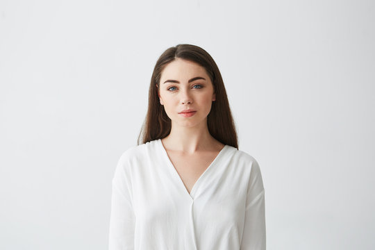 Portrait of young beautiful businesswoman looking at camera smiling over white background.