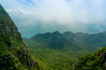 Obraz premium Beautiful tree covered mountains fading into the distance with cloudy skies and fog rolling between them. Shot in Langkawi near the Machincang mountain