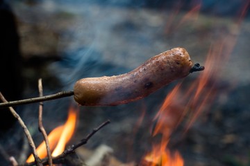 The sausage is fried on an open fire with a red and spicy sauce and is ready for use. Prepared during a hiking trip.