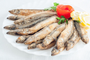 sprat anchovy fish with lemon on a white plate