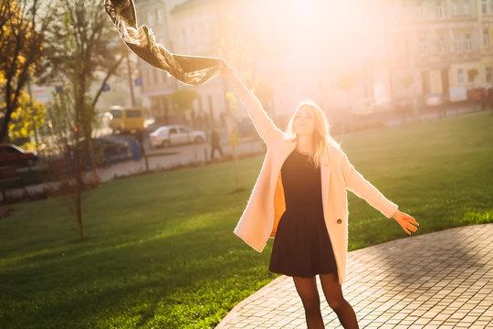 Happy girl throwing her scarf freely in morning city during warm