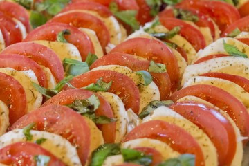 Healthy tomatoes and mozzarella chopped in salad starter row. Wonderful vegetarian vegan appetizer. Green, bio and local food. Tomato and cheese in rows with herbs and basil. Delicious nutrition