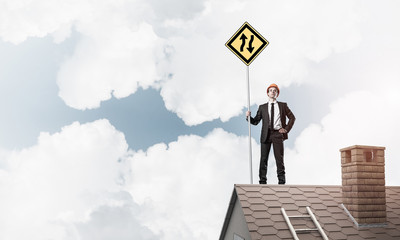 Engineer man on brick roof with sign in hands. Mixed media