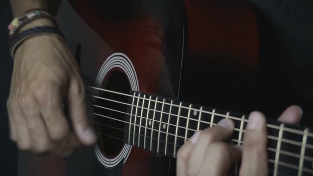 Man playing guitar on black background. Six strings. Playing with fingers