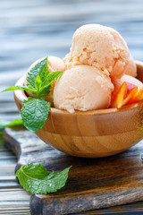 Homemade peach ice cream in a wooden bowl.