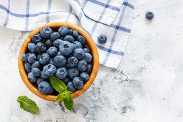 Ripe blueberries and mint in a wooden bowl.