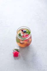 Water with ice cubes with berries and herbs in the form of a star in a glass