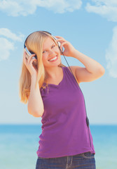 Portrait of blonde girl with headphone on the beach.