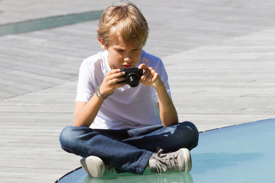 Young boy with a digital camera taking pictures outdoors