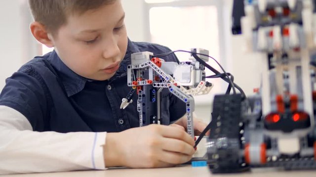 Young boy engineer playing with robot. Close-up.