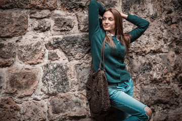 Young woman standing on old stone wall, copy space, ancient