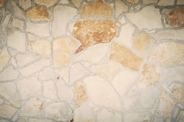 A wall made of stone, irregular but compact rocks. Background shadowed texture.
