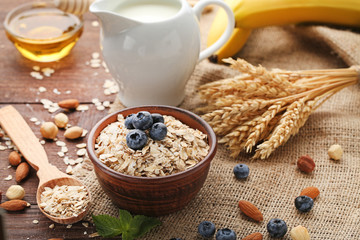 Oat flakes in bowl with blueberries on wooden table