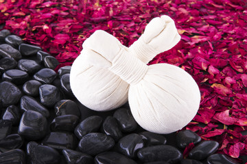 Spa. Herbal balls on the background of black pebbles and dried rose petals.