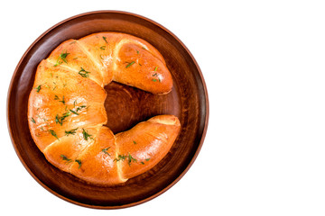 Freshly baked large  croissant, sprinkled with dill. On a clay dish. Isolated on white background. flat, top viwe.