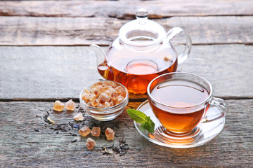 Cup of tea with teapot and sugar on grey wooden table