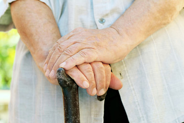 Hands of old senior with walking stick