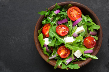 Fresh salad with arugula, feta cheese, red onion in a bowl