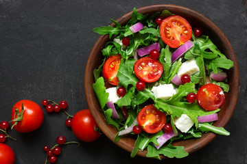 Fresh salad with arugula, feta cheese, red onion and red currant in a bowl
