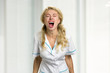 Young nurse screaming in despair. Very stressed beautiful young female doctor screaming loudly in frustration with closed eyes.