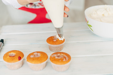 A young girl decorates cupcakes with cream.