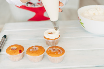 A young girl decorates cupcakes with cream.