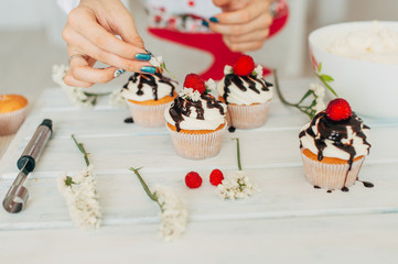 A young girl decorates cupcakes with fresh berries and flowers