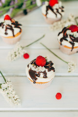 Delicate tasty muffins decorated with raspberries and poured with chocolate.