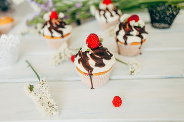Delicate tasty muffins decorated with raspberries and poured with chocolate.