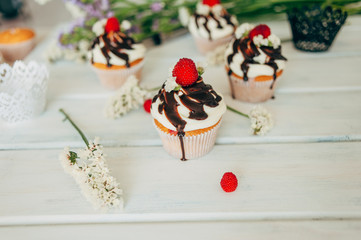 Delicate tasty muffins decorated with raspberries and poured with chocolate.