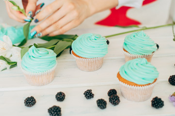 A young girl decorates cupcakes with fresh berries and flowers