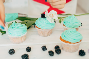 A young girl decorates cupcakes with fresh berries and flowers