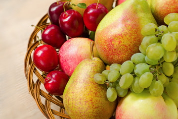 Fruit harvest. Organic fresh apples, pears, grapes and plums in a woven wooden plate