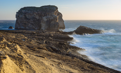 Gozo Island cliffs with Fungus Rock (small islet) during the spring storm. Dwejra, Maltese archipelago