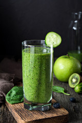 Green smoothie in glass. Healthy cleansing detox drink for sports, yoga, healthy lifestyle. Vertical, closeup view, black background