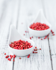 Portion of Pink Peppercorns on wooden background, selective focus