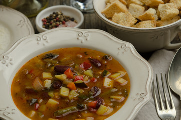 Vegetables soup served with croutons, rustic background 