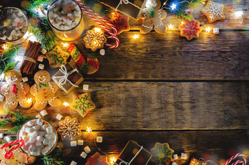 Dark wooden background with cocoa, gingerbread cookies, Christmas trees and gifts