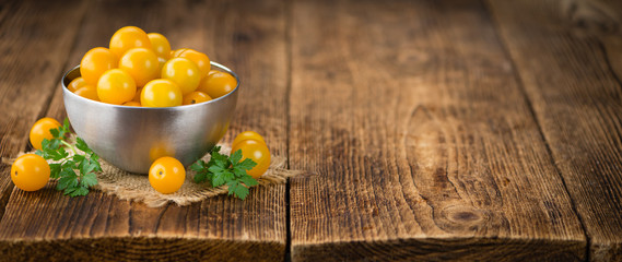 Yellow Tomatoes on wooden background; selective focus